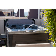 Platinum Spas Topaz Whirlpool mit sprudelndem Wasser auf moderner Dachterrasse, umgeben von grünen Pflanzen und Stadtblick