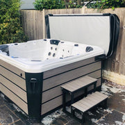 VX2 Cover Lifter montiert an einem Whirlpool mit Holzoptik – Abdeckung geöffnet und elegant hinter dem Spa positioniert