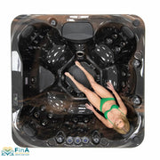 Produktname: Platinum Spas Seville Outdoor Whirlpool – Deluxe, für bis zu 7 Personen. Draufsicht auf das Modell in Midnight Dark mit einer Frau in grünem Bikini, die im Whirlpool liegt.