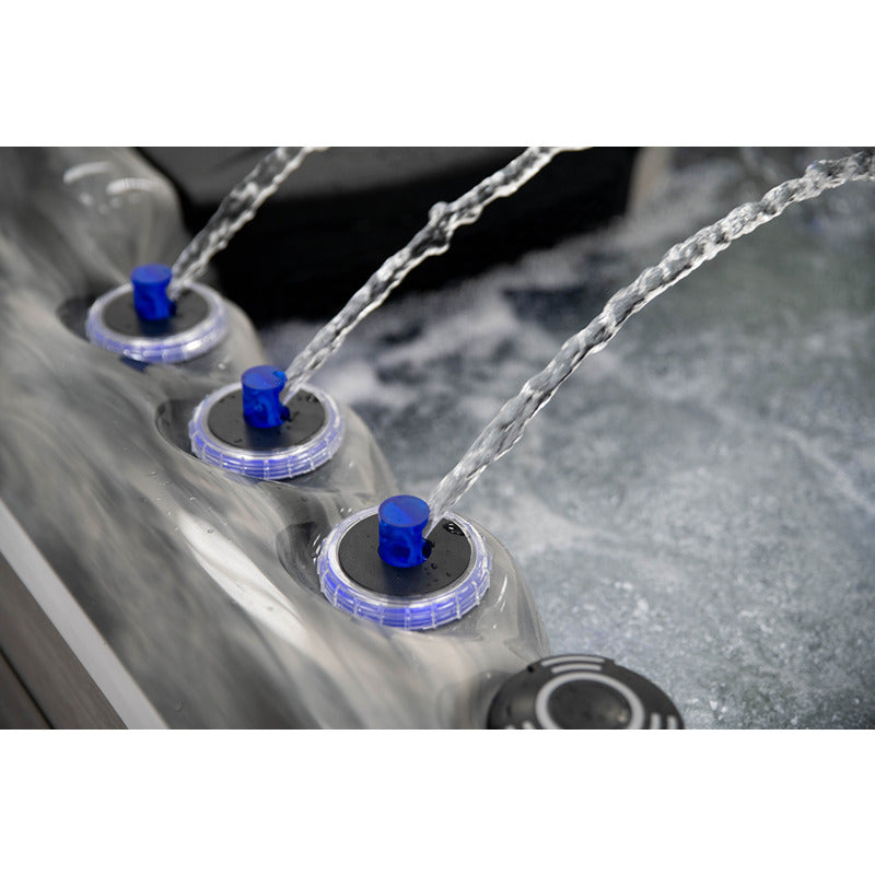 Detailaufnahme des Platinum Spas Refresh Outdoor Whirlpool – drei Wasserfontänen mit blauer LED-Beleuchtung und elegantem Rand in Marmoroptik