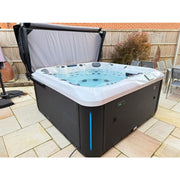 Platinum Spas Florence Outdoor Whirlpool mit schwarzem Rahmen und türkisblauem Wasser auf Terrassenstein, offene Abdeckung im Hintergrund sichtbar
