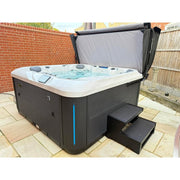 Platinum Spas Florence Outdoor Whirlpool mit grauem Rahmen und weißem Becken, geschlossener Abdeckung und Einstiegsstufen auf Terrasse