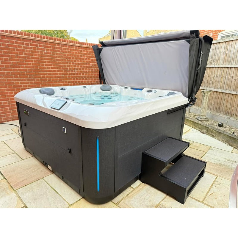 Platinum Spas Florence Outdoor Whirlpool mit grauem Rahmen und weißem Becken, geschlossener Abdeckung und Einstiegsstufen auf Terrasse