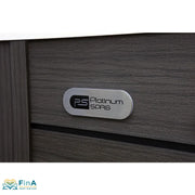 Nahaufnahme des Platinum Spas Logos auf der anthrazitfarbenen Außenverkleidung des St Tropez Deluxe Whirlpools – gebürstetes Metallschild auf Holzstruktur, präsentiert von FinA Wellness Store.