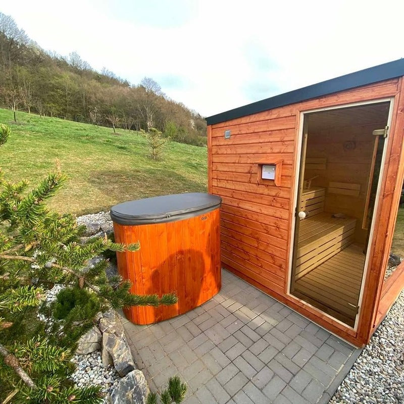 Polar Spa Standard Eisbad aus orangem Thermoholz neben rotem Saunahaus in parkähnlicher Gartenlandschaft
