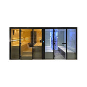 Tylö Panacea Twin Sauna und Dampfbad Kombination mit schwarzem Rahmen, links goldgeleuchtete Holzsauna, rechts blaues LED-beleuchtetes Dampfbad mit Glastüren