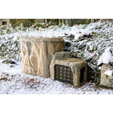 Outdoor-Sauna aus Naturstein im verschneiten Garten mit schwarzem Gitter-Eingang und rustikaler Fassade