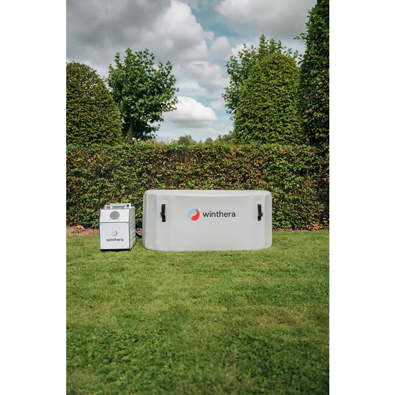 Winthera Flex Eisbad in Weiß mit externer Wärmepumpe im Garten auf grünem Rasen, umgeben von grünen Hecken