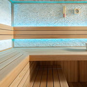Innenansicht der AWT E1601C Sauna aus roter Zeder mit blauer LED-Beleuchtung, L-förmiger Holzbank und Natursteinwand
