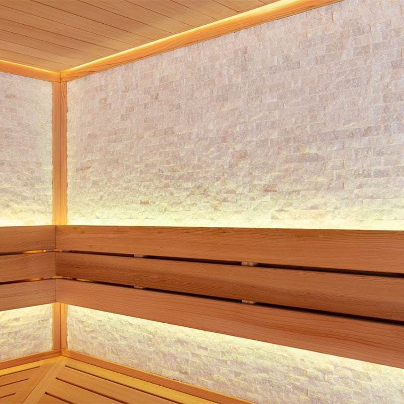 Detailansicht der Natursteinwand und Sitzbänke in der AWT E1603B Sauna aus roter Zeder mit indirekter Beleuchtung