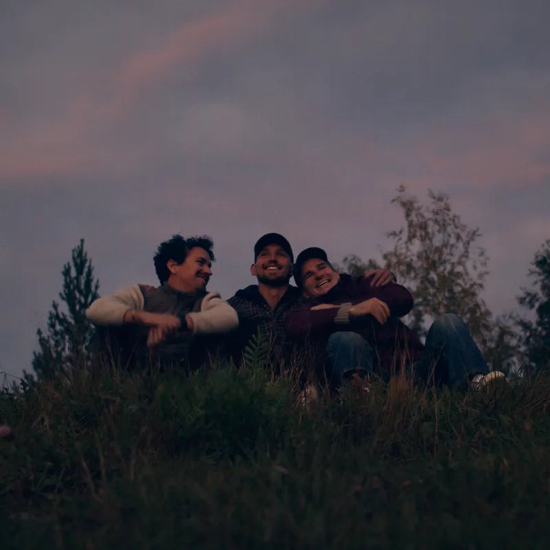 Bast Näver Premium Zeltsauna: Drei Personen genießen entspannte Zeit in der tragbaren Sauna in der Natur bei Dämmerung