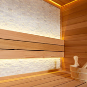 Detailansicht der Sitzbank und Natursteinwand in der AWT E1604B Sauna aus roter Zeder mit indirekter Beleuchtung