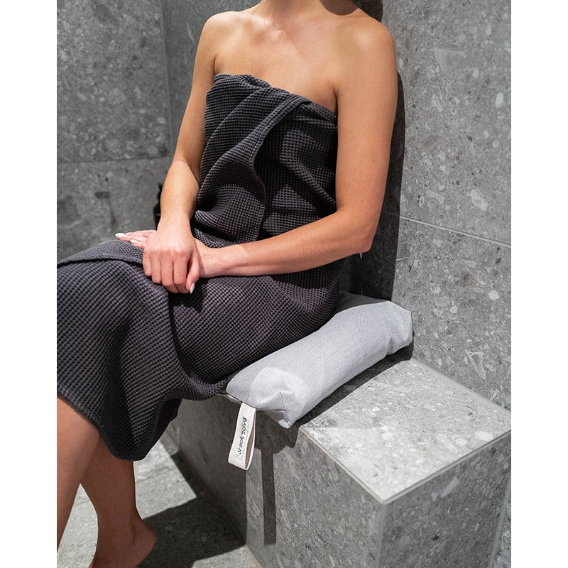 Frau sitzt im Dampfbad auf weißem Badesofa Duschkissen – gepolsterter Sitzkomfort für Wellnessbereiche