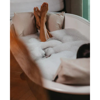 Entspannte Füße auf dem Badesofa Fußkissen in einer mit Schaum gefüllten Badewanne