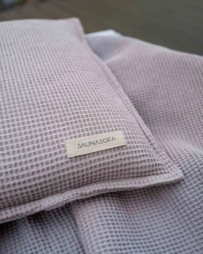 Nahaufnahme des Badesofa Saunakissens mit „SAUNASOFA“-Label in Rose aus Waffelpiqué Stoff