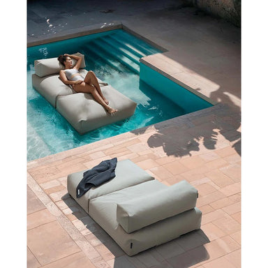 Frau entspannt auf dem schwimmenden POOLSOFA Double im Pool, weitere Liege auf der Terrasse