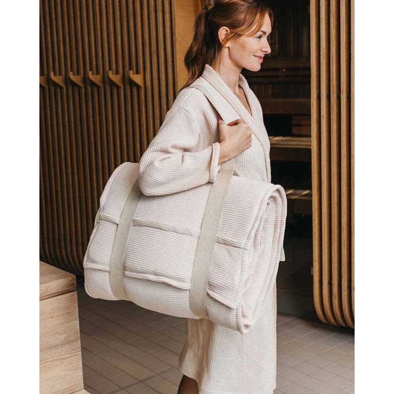 Frau trägt gepolsterte Saunaauflage Long mit Gurt im Spa-Bereich – Farbe Perlmutt