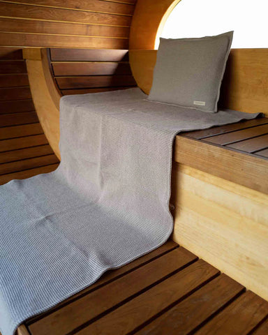 Badesofa Saunakopfkissen und ausgebreitetes Saunatuch aus Waffelpiqué in einer modernen Holzsauna
