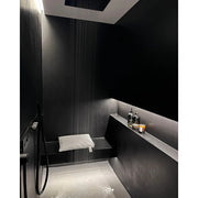 Badesofa Sitzkissen in eleganter schwarzer Dusche mit indirekter Beleuchtung und Regenduschkopf.