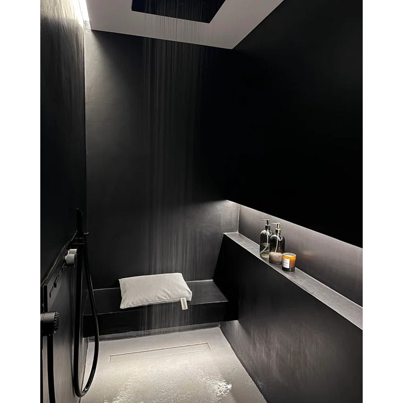Badesofa Sitzkissen in eleganter schwarzer Dusche mit indirekter Beleuchtung und Regenduschkopf.
