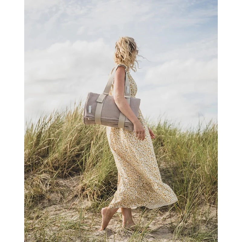 Frau trägt das Badesofa Strandsofa stilvoll durch die Dünen – entspannt unterwegs mit Komfort und Leichtigkeit.