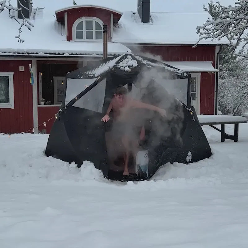 Bast Björk Basic Saunazelt - 4-10 Personen Pop-up Sauna im Schnee mit dampfender Öffnung, Person im Inneren sichtbar