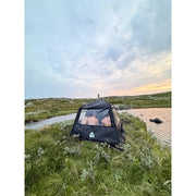 Bast Björk Deluxe Zeltsauna in schwarzer Farbe in natürlicher Landschaft am Wasser aufgebaut, tragbare Gartensauna für bis zu 10 Personen