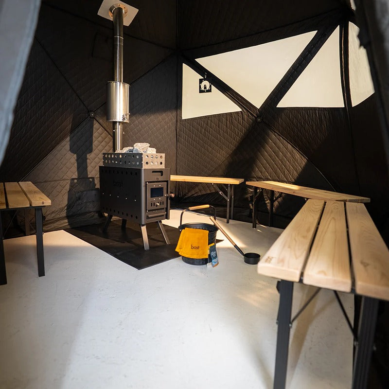 Innenraum der Bast Björk Deluxe Zeltsauna mit drei Saunabänken und Ofen