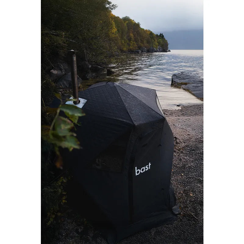 Bast Björk Premium Zeltsauna am Seeufer, tragbare Gartensauna in schwarzem Design mit Bast-Logo