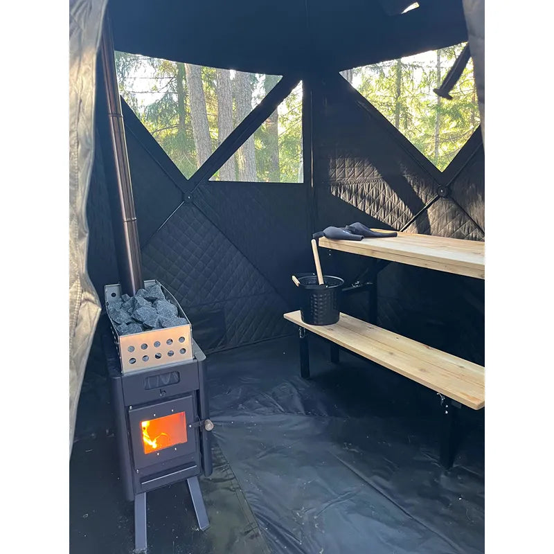 Bast Näver Deluxe Zeltsauna Innenraum mit brennendem Ofen, Holzbänken und Sichtfenstern ins Waldgrün