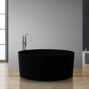 Freistehende Mineralguss Badewanne in Schwarz mit integrierter Armatur auf Holzboden vor hellgrauer Wand in modernem Badezimmer