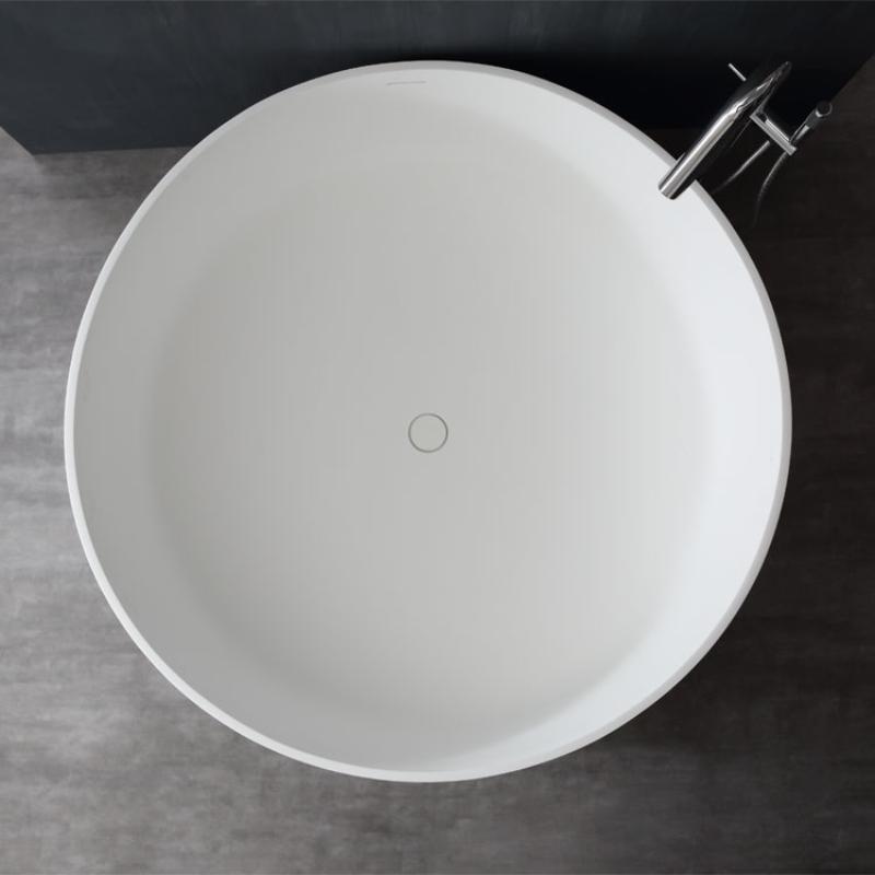 Weiße freistehende Mineralguss Badewanne EAGO AWT StoneArt BS-507 von oben, rundes Design mit verchromter Armatur seitlich angebracht, moderne Badezimmereinrichtung auf Betonboden.