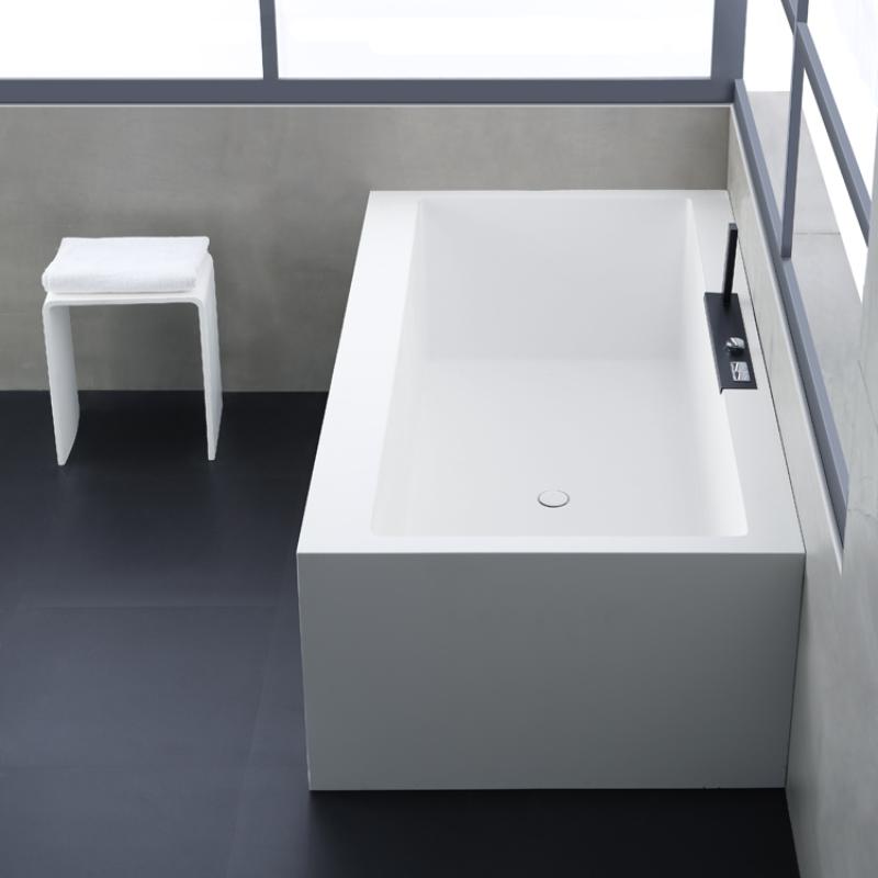Freistehende weiße Mineralguss Badewanne EAGO AWT StoneArt BS-535 mit modernem Design im Badezimmer, daneben ein weißer Hocker