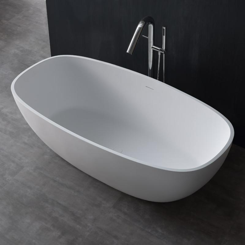 Freistehende moderne Badewanne EAGO AWT StoneArt BS-552 in Weiß mit ovaler Form und glatter Mineralguss-Oberfläche, dahinter Standarmatur aus Chromstahl vor schwarzer Wand