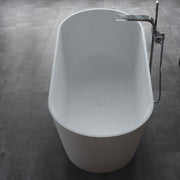 Freistehende Mineralguss Badewanne EAGO AWT StoneArt BS-553 in Weiß mit moderner ovaler Form und schwarzer Standarmatur auf grauem Untergrund.