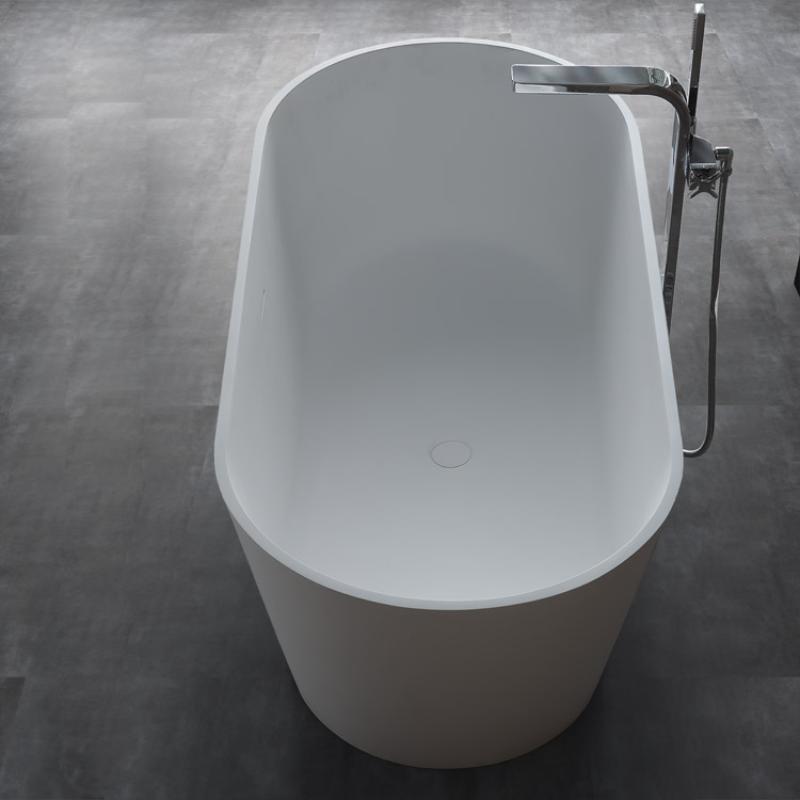 Freistehende Mineralguss Badewanne EAGO AWT StoneArt BS-553 in Weiß mit moderner ovaler Form und schwarzer Standarmatur auf grauem Untergrund.