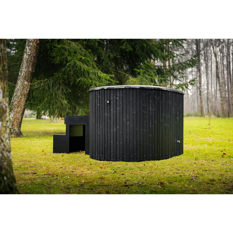 Celsium Aiste Eisbad Grand in Ebony mit Kühlgerät und Treppe im natürlichen Gartenumfeld.