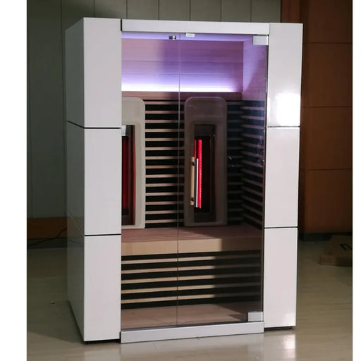 Delta SPA COLORINA full spectrum Infrarot-Sauna mit weißem Außengehäuse, schwarzen Holzbänken und aktivierten roten Infrarot-Strahler sowie lila Chromotherapie-Beleuchtung