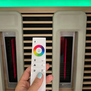 Delta SPA COLORINA full spectrum Infrarot-Sauna mit Farblichtkontroller in Hand, Infrarotstrahler sichtbar