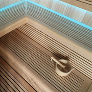Innenansicht der Hemlock-Sauna AWT E1112C mit Holzbänken, LED-Beleuchtung an der Decke und Saunakelle auf der Liege