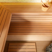 Innenansicht der EAGO AWT E1602C Hemlock Sauna mit Holzbänken, heller Holzverkleidung und Saunazubehör wie Eimer und Kelle auf der Ablagefläche