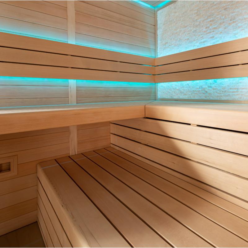 Modernes Saunainneres mit hellen Holzbänken, türkiser LED-Beleuchtung an Wänden und Decke, natürliches Lärchensperrholz, Design der AWT E1602C