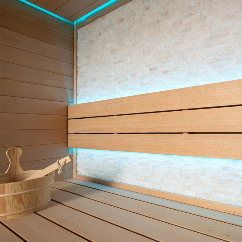 Modernes Saunainnenraum mit Holzbänken aus Hemlock, Ziegelmauer und türkiser LED-Beleuchtung an Decke und Wand