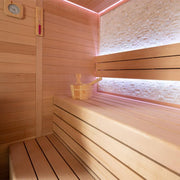 Modernes Saunainneres aus Hemlock-Holz mit zwei Sitzbänken, Thermometer, Holzeimer und rosa LED-Beleuchtung an den Wänden