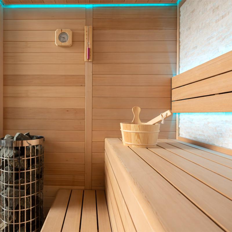 Innenansicht der EAGO AWT E1604C Hemlock Sauna mit Holzbänken, Saunaofen, Thermometer und Saunakübel auf der Bank