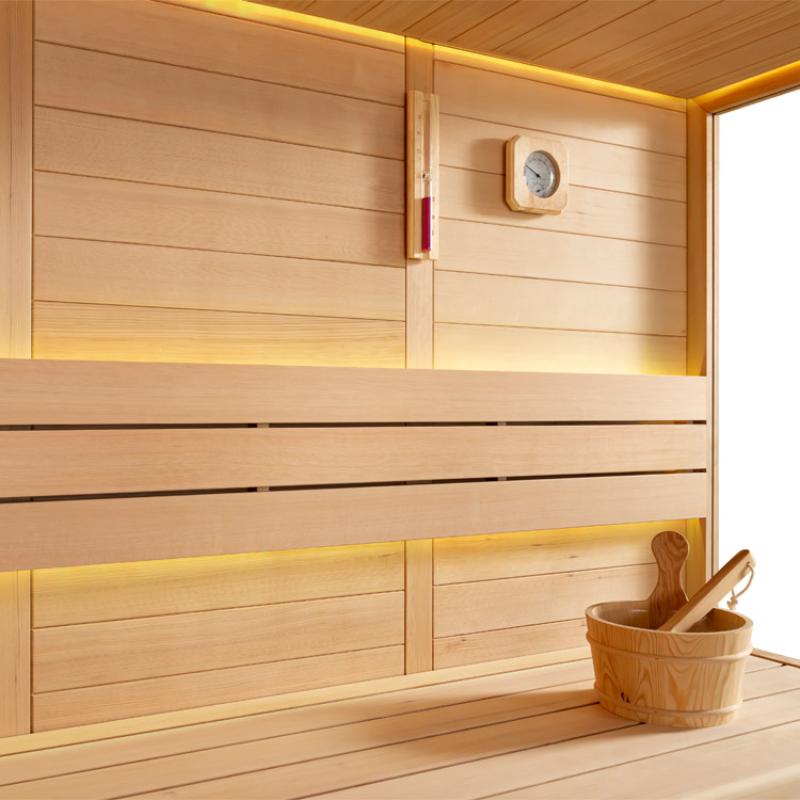 Modernes Saunainneres mit Holzverkleidung, LED-Beleuchtung, Thermometer und Holzeimer mit Kelle auf der Bank der EAGO AWT E1611C