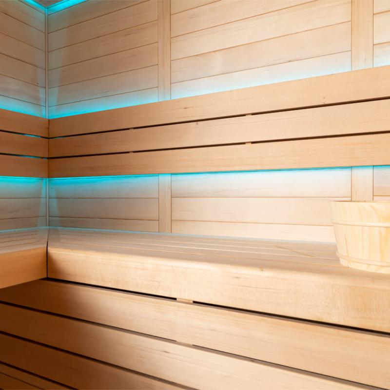 Modernes Saunainneres mit hellen Holzbänken, türkiser LED-Beleuchtung und horizontalen Holzpaneelen an den Wänden der EAGO AWT E1612B Hemlock Sauna.