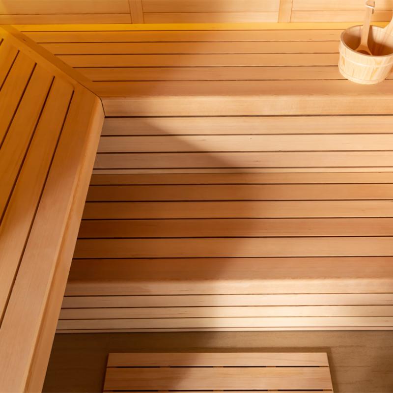 Innenansicht der EAGO AWT E1612B Hemlock Sauna mit Holzbänken und horizontalen Holzwänden aus Hemlock-Holz, Saunakübel oben rechts sichtbar