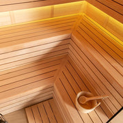 Innenansicht einer Holzsauna mit Bänken aus hellem Hemlock-Holz, Aufgusseimer und LED-Beleuchtung von oben