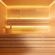 Modernes Saunainneres mit Holzbänken, wärmender LED-Beleuchtung und Saunazubehör wie Kelle und Eimer auf der oberen Bank
